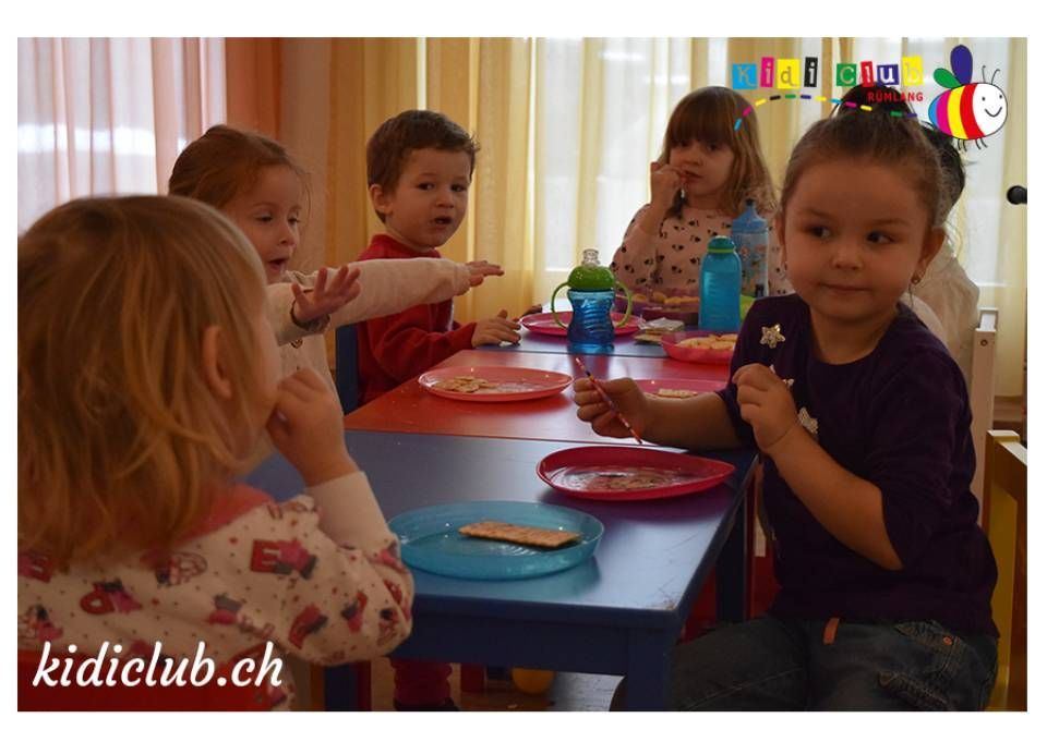 Eine Gruppe Kinder sitzt mit Tellern voller Essen an einem Tisch.
