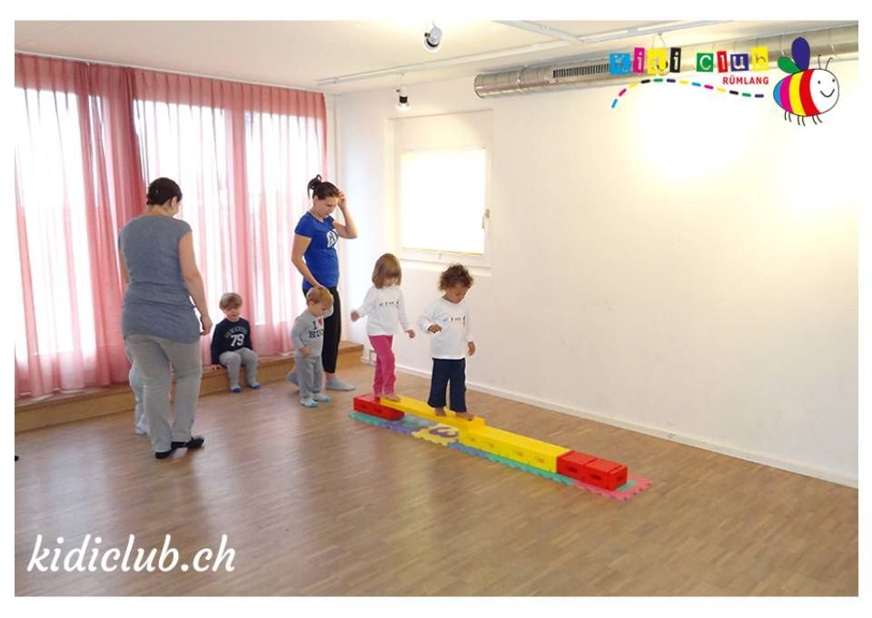 Eine Gruppe Kinder spielt in einem Raum auf einem Schwebebalken.