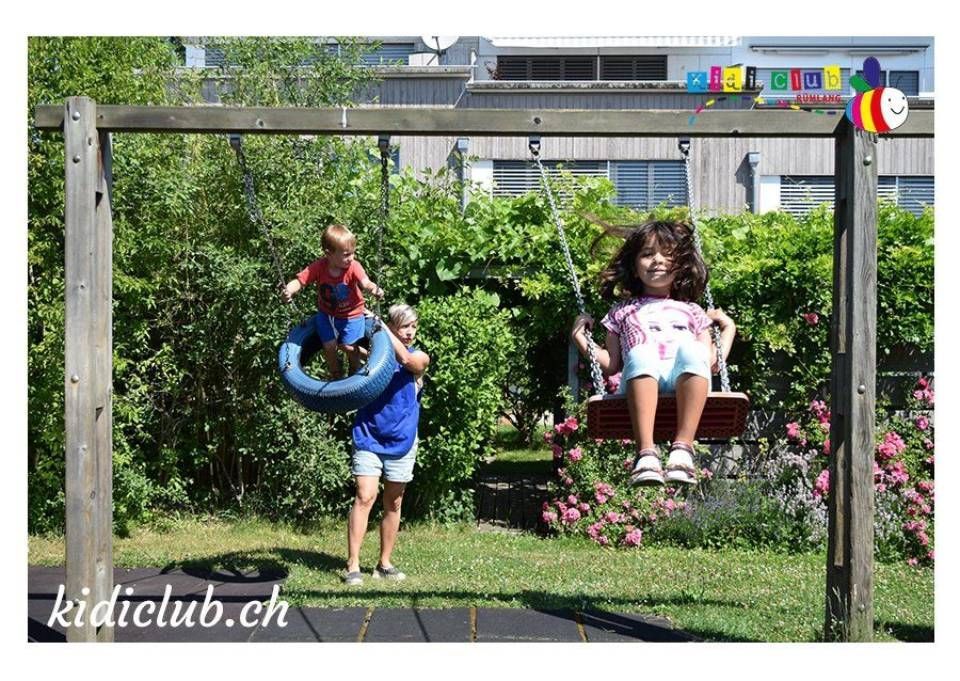 Ein Mädchen sitzt auf einer Schaukel, während ein Junge auf einer Reifenschaukel klettert.