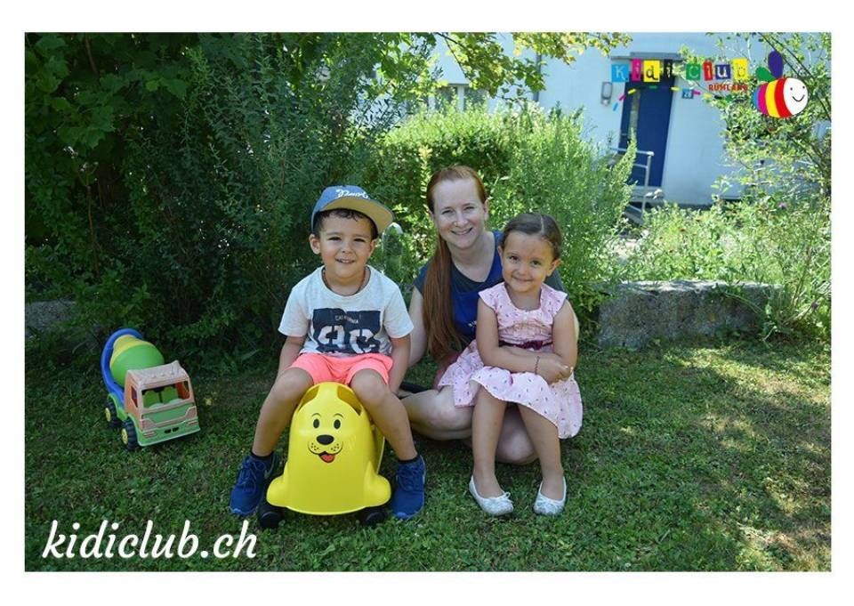 Eine Frau und zwei Kinder posieren im Gras für ein Foto.