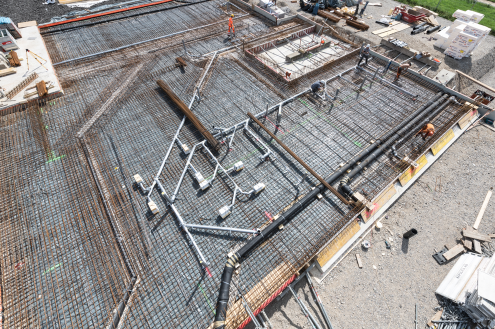 Baustelle mit Bewehrungsmatten, Betonschalungen und Arbeitsschutzgeländern auf einer Bodenplatte