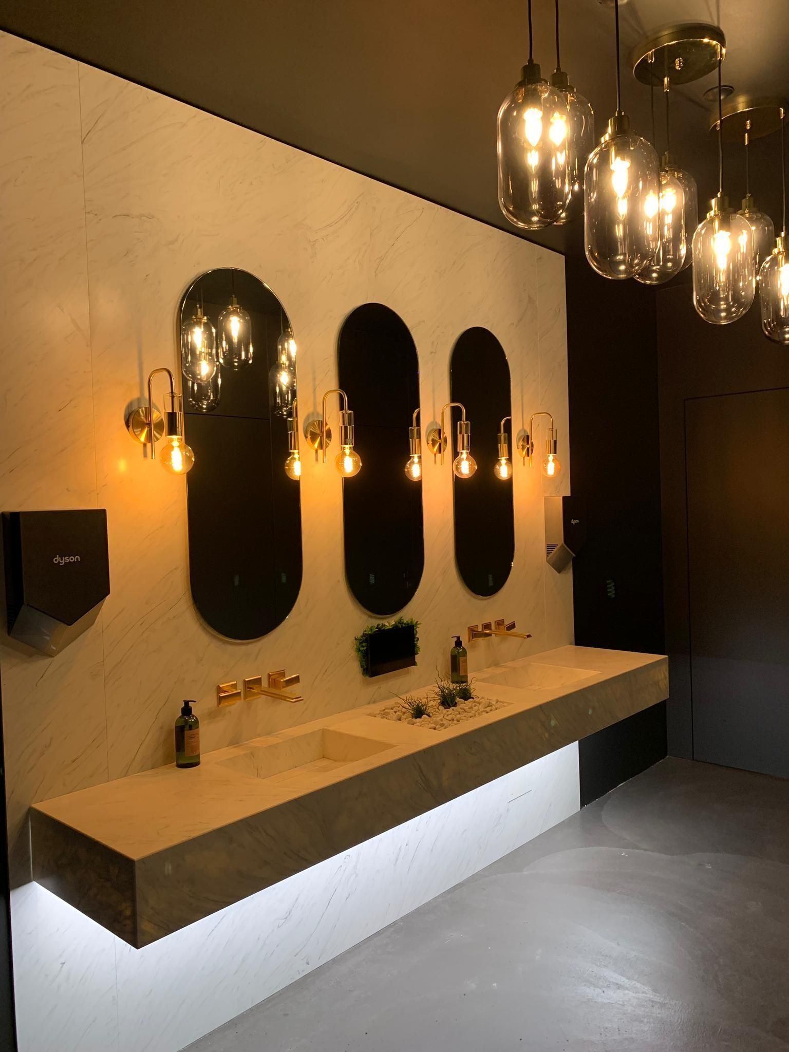 Modernes Badezimmer mit Betonarbeitsplatte, ovalen Spiegeln und Hängeleuchten.
