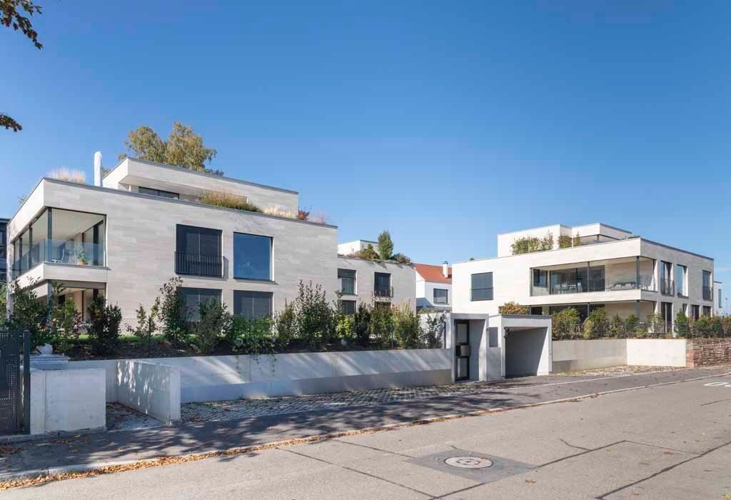 Moderne weiße Wohnhäuser säumen eine ruhige Straße unter einem klaren blauen Himmel