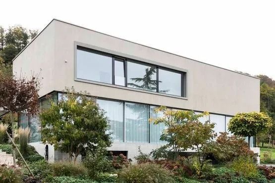 Modernes zweistöckiges Haus mit großen Fenstern und umgebender Vegetation