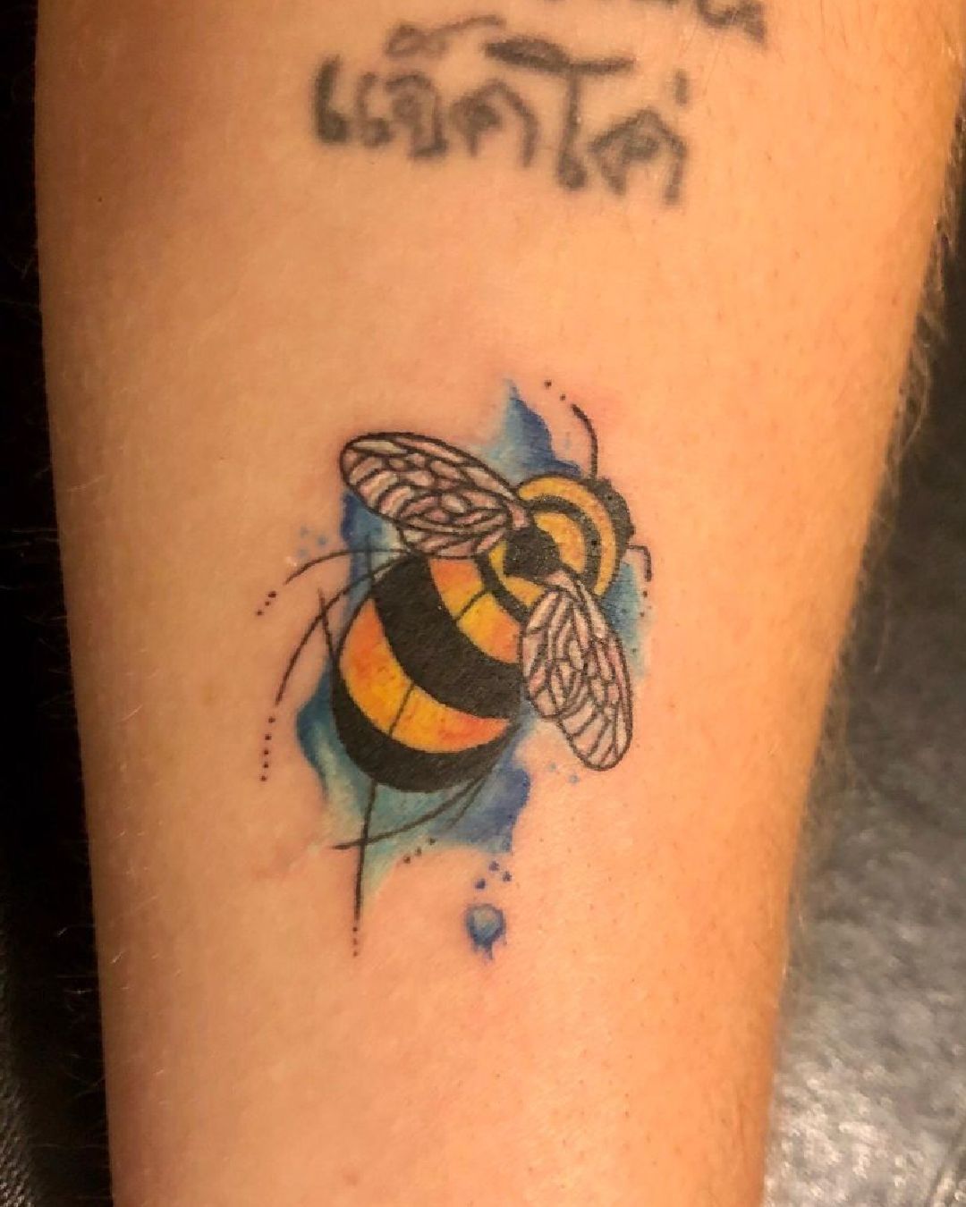 Eine Person hat eine Bienentätowierung auf dem Arm.
