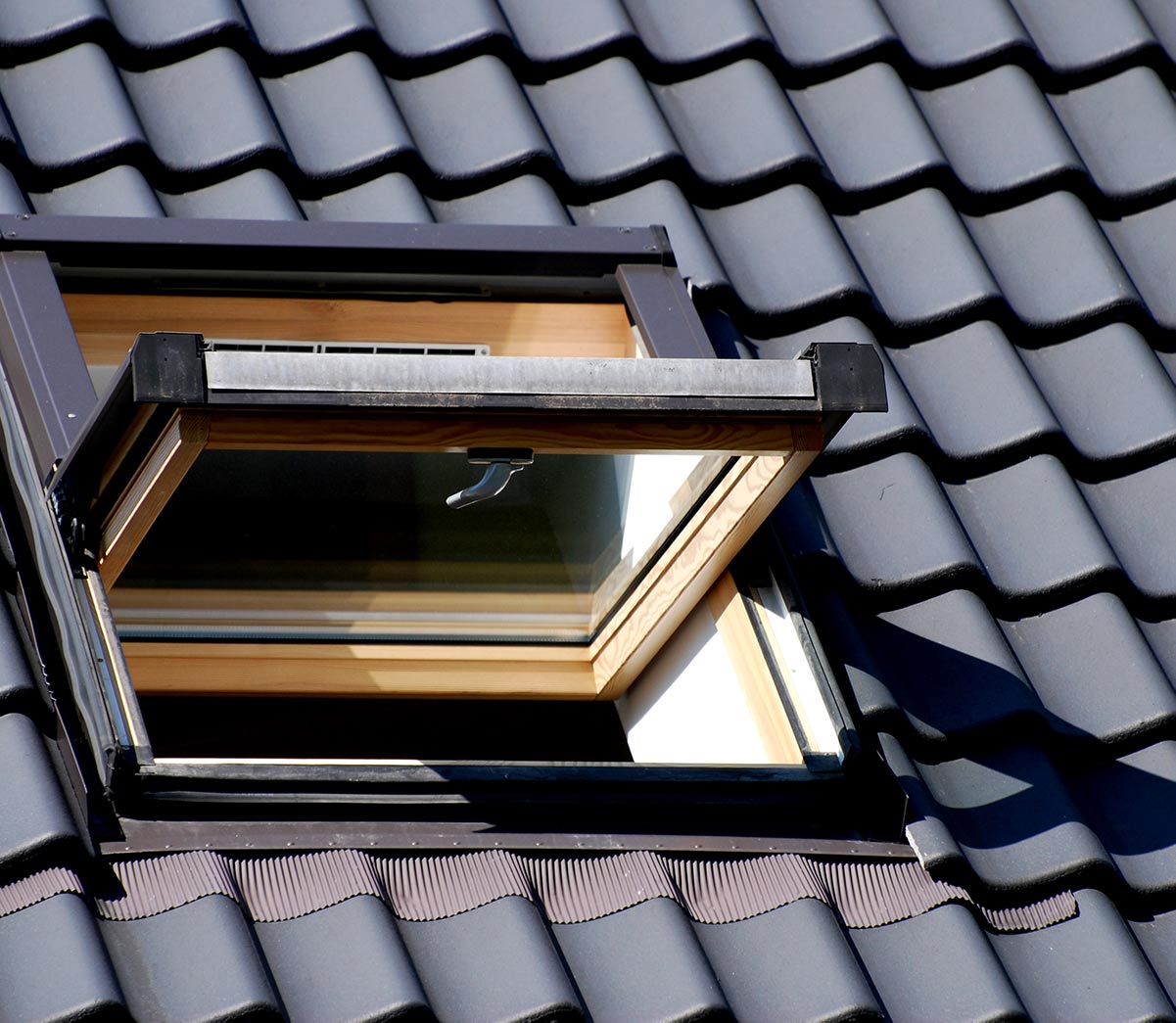 Fenêtre de toit sur une toiture à tuiles sombres