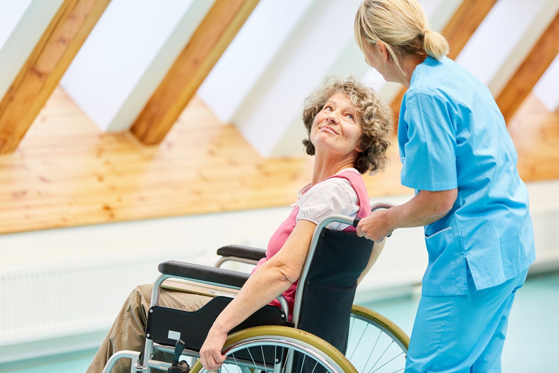 Eine Frau im Rollstuhl wird von einer Krankenschwester unterstützt