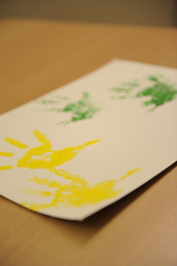 Blatt Papier mit Handabdrücken in Grün und Gelb