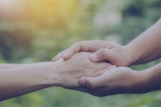 Hand wird von zwei Händen gehalten