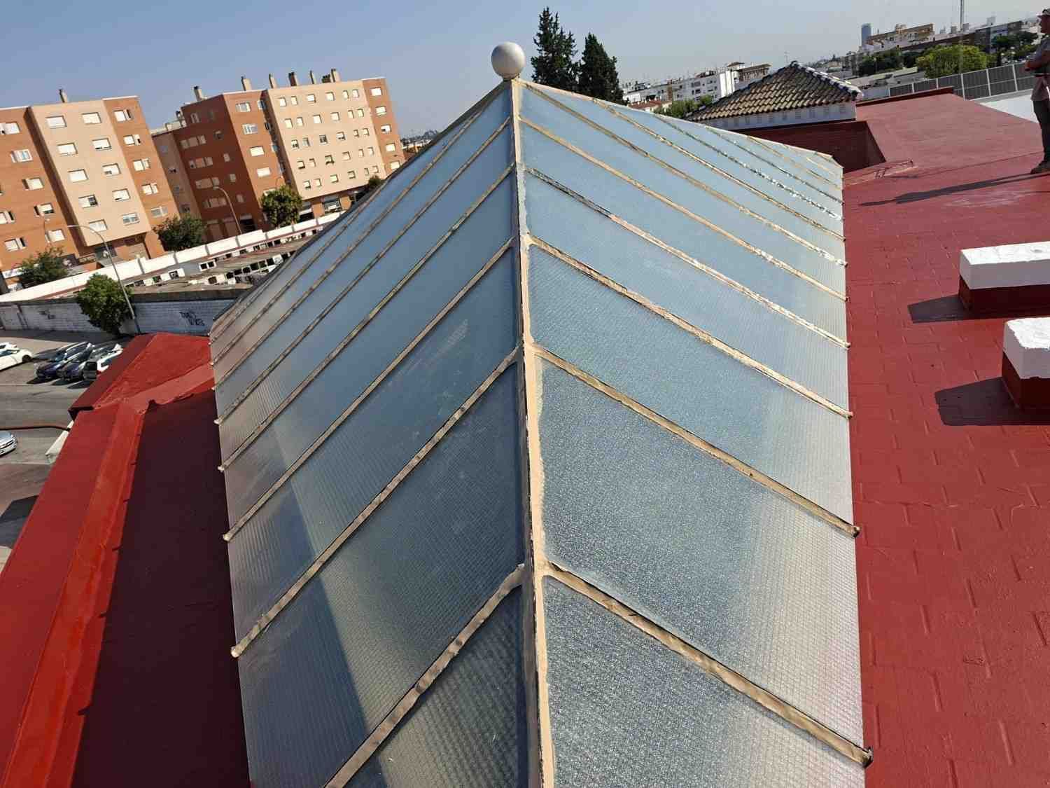 Alargada claraboya de cristal en un tejado rojo de un barrio urbano.