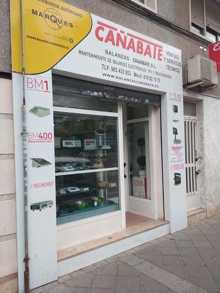 Pequeña tienda con escaparate de cristal y un letrero rojo y blanco que dice 