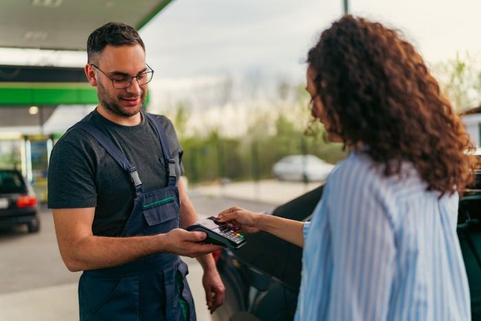 Frau bezahlt mit Karte an einer Tankstelle