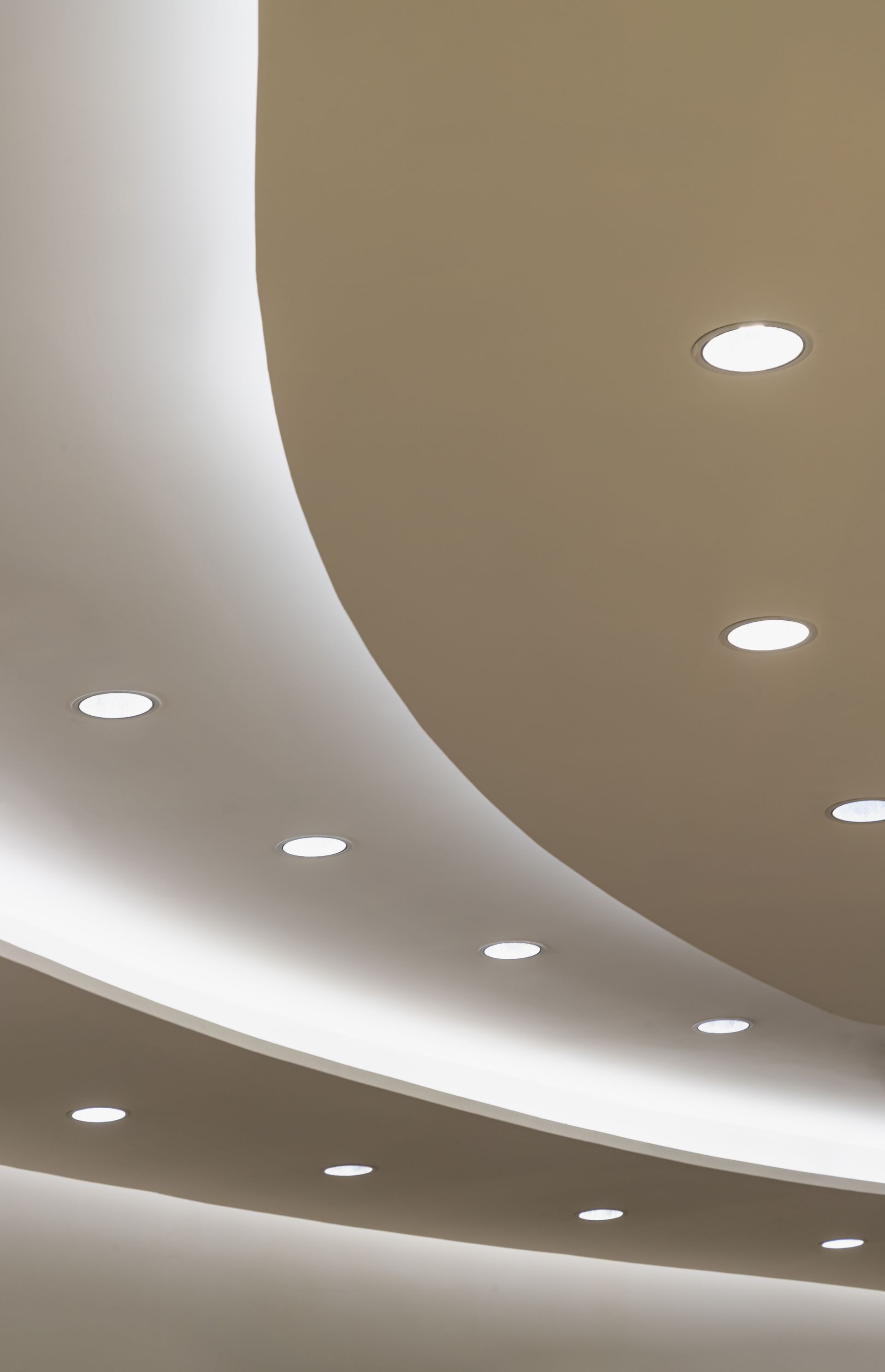 Plafond incurvé avec spots ronds encastrés dans un intérieur moderne.