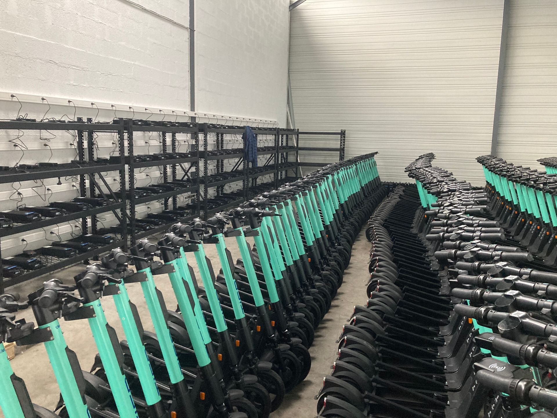 Des rangées de scooters électriques verts alignés dans un entrepôt.