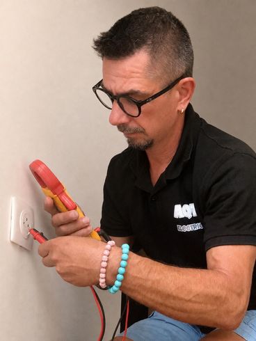 Un homme utilise un testeur de tension sur le fil d'une prise électrique.