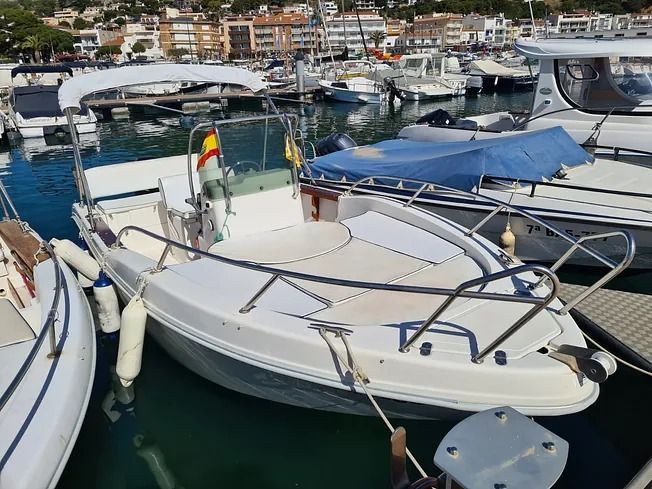 Un barco blanco está atracado en un puerto deportivo con otros barcos.
