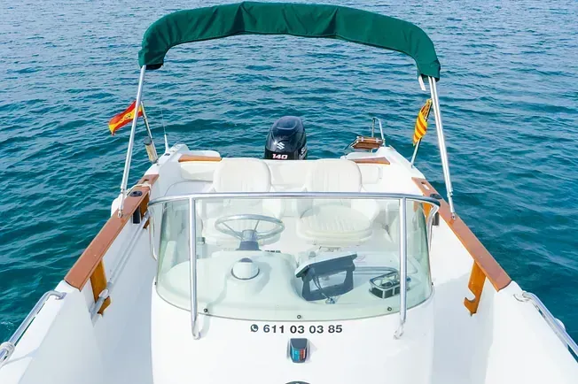 Un barco blanco con un dosel verde flota sobre un cuerpo de agua.
