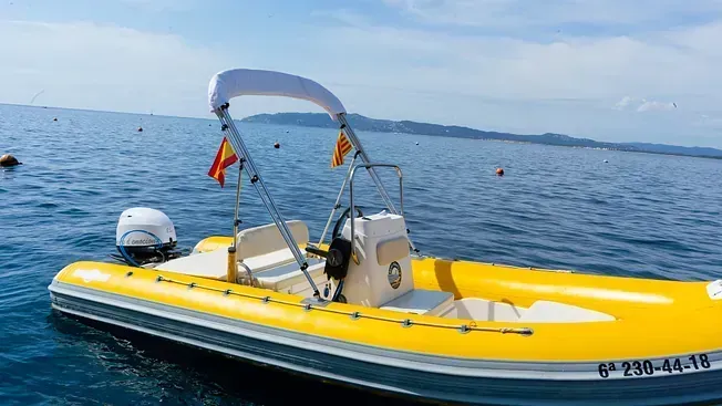 Un barco amarillo y blanco flota sobre un cuerpo de agua.