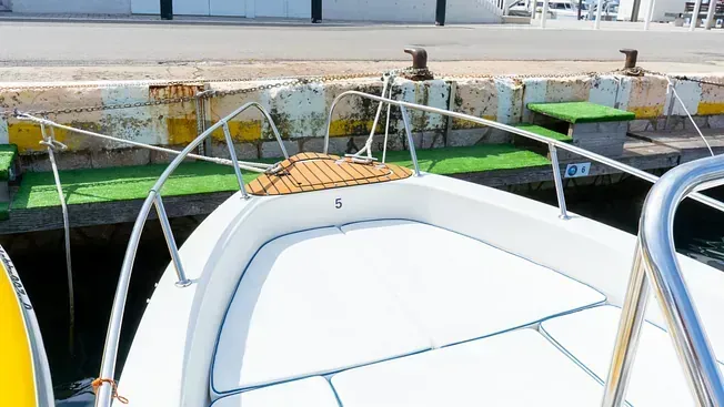 Un barco blanco con cubierta de madera está atracado en un muelle.
