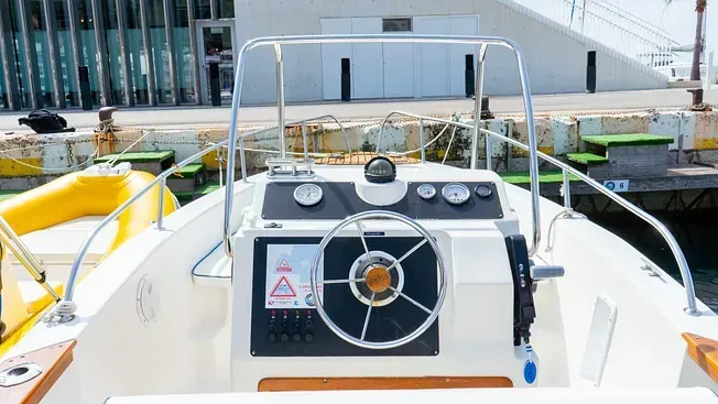 Un barco blanco con un volante está atracado en un puerto.