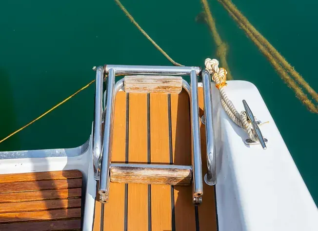 Un barco con una escalera atada a un costado está atracado en el agua.