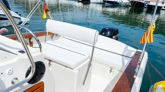 Un pequeño barco blanco está atracado en un puerto.