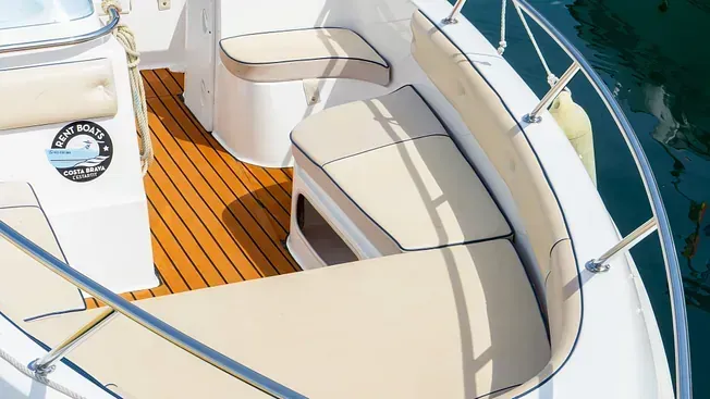 Un barco blanco con cubierta de madera flota sobre un cuerpo de agua.