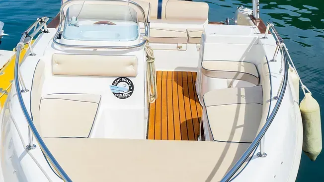 Un barco blanco con cubierta de madera flota sobre un cuerpo de agua.