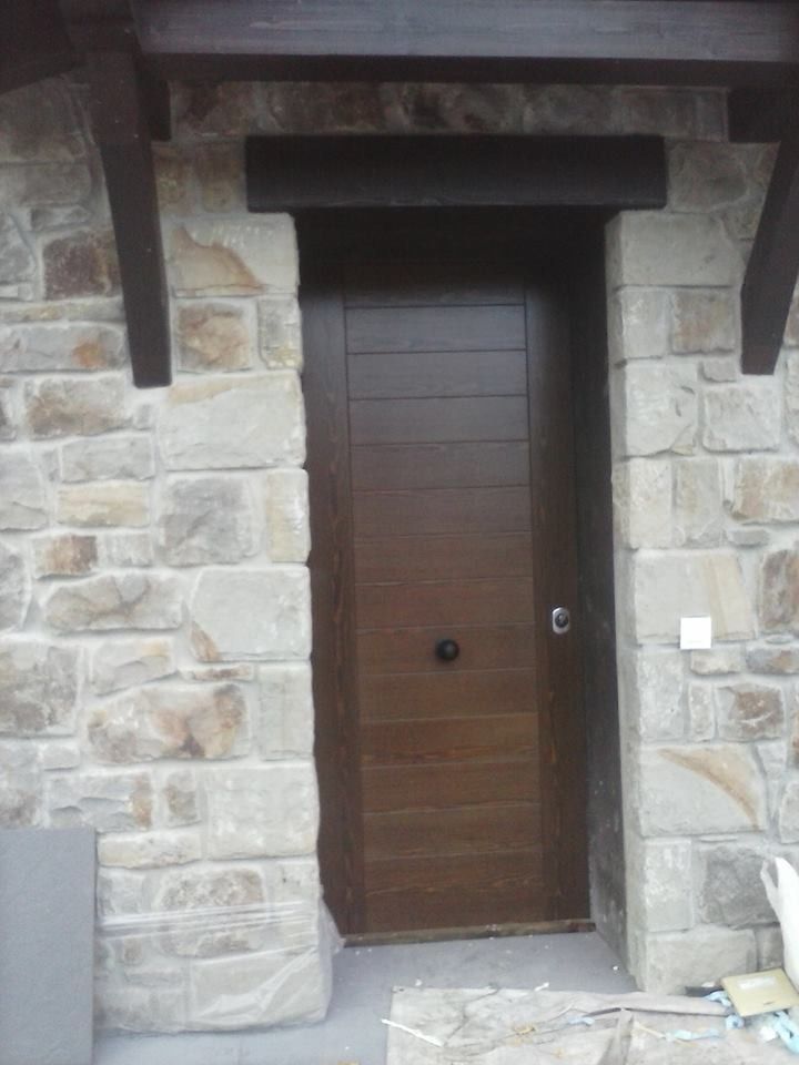 Una puerta de madera con una pared de piedra detrás.