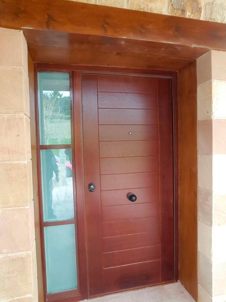 Una puerta de madera con una ventana de vidrio se encuentra en un edificio de piedra.