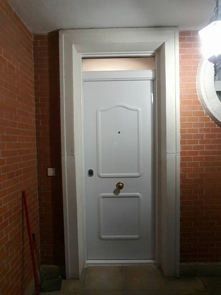 Una puerta blanca está en un pasillo al lado de una pared de ladrillos.