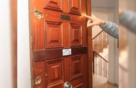 Una persona señala una puerta de madera en un pasillo.