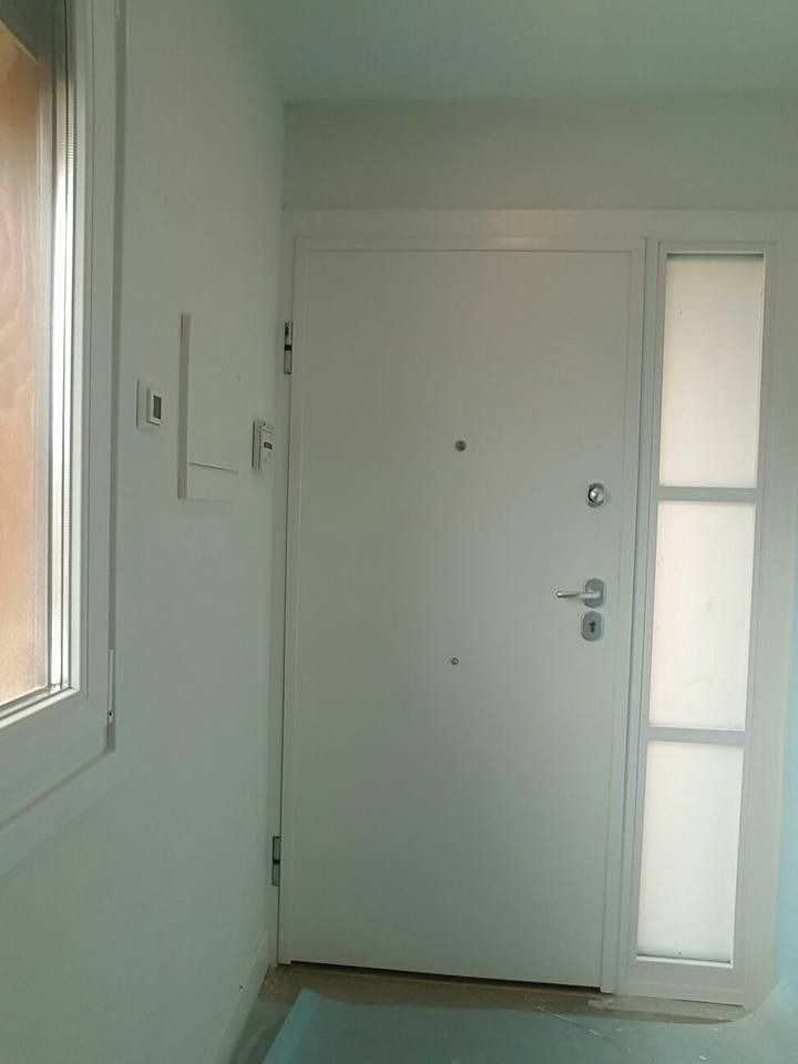 Una puerta blanca con una ventana en un pasillo.