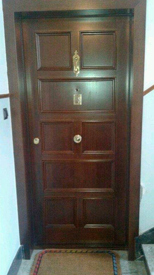 Una puerta de madera está en un pasillo al lado de una escalera.