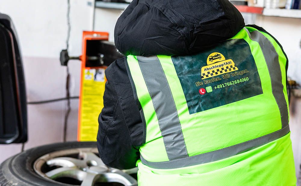 Ein Mann mit einer gelben Sicherheitsweste arbeitet an einem Reifen.