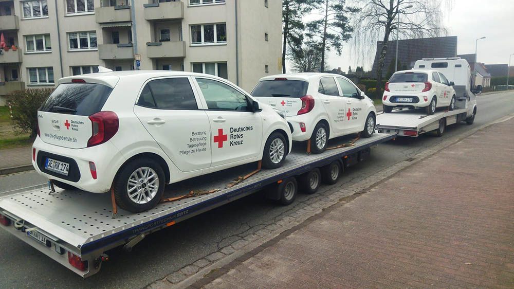 Drei Autos werden von einem Abschleppwagen eine Straße entlang geschleppt.