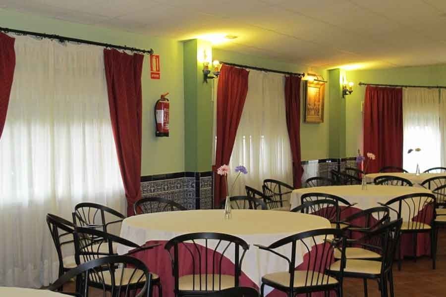 Una habitación con mesas y sillas y un extintor en la pared.