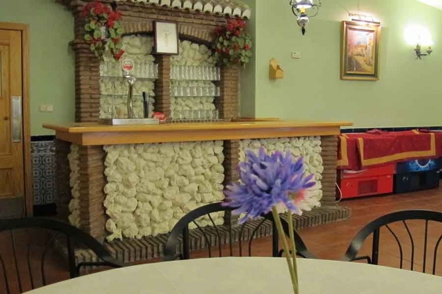 Una flor morada está sobre una mesa frente a un bar.