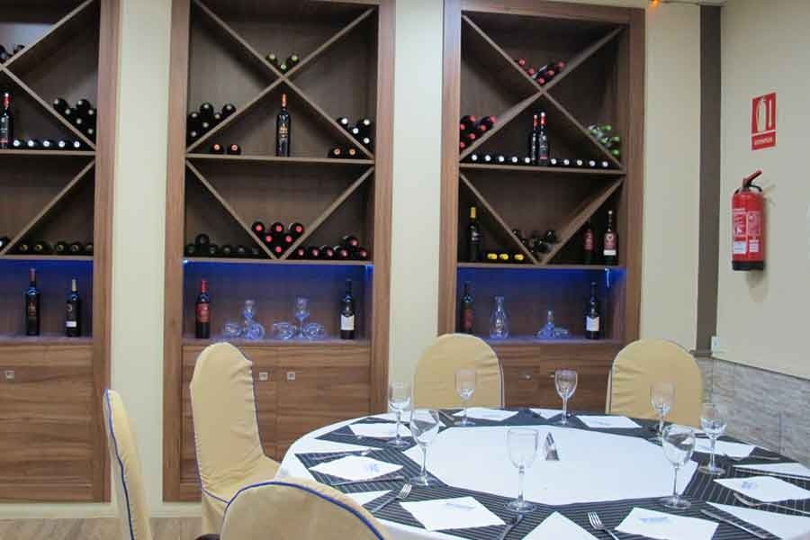 Una habitación con una mesa y sillas y estantes con botellas de vino.