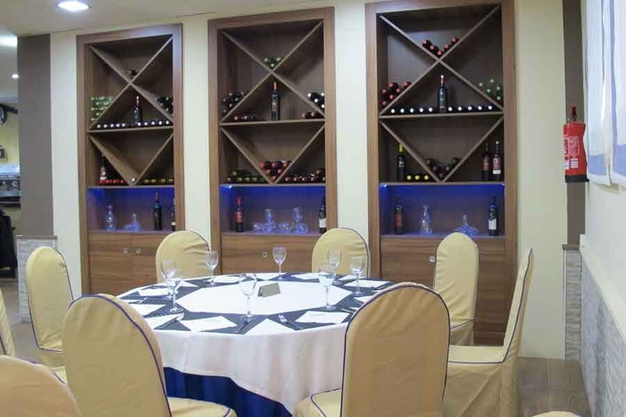 Un comedor con una mesa y sillas y estantes llenos de botellas de vino.