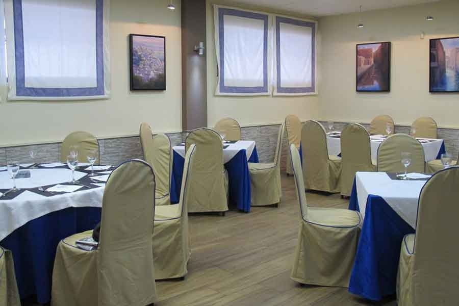 Un comedor con mesas y sillas con fundas azules.