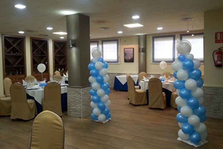 Una habitación con mesas y sillas decoradas con globos azules y blancos.