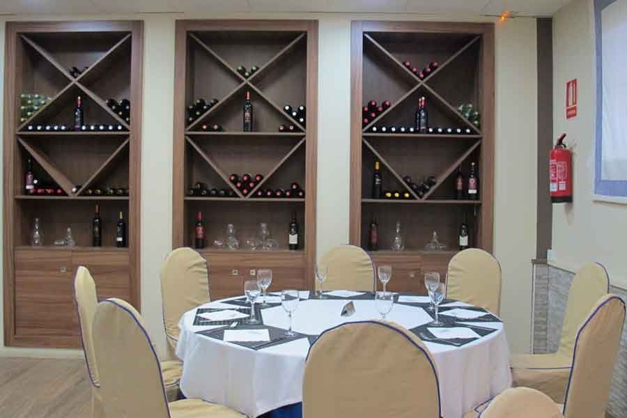 Un comedor con una mesa redonda y sillas y estantes llenos de botellas de vino.