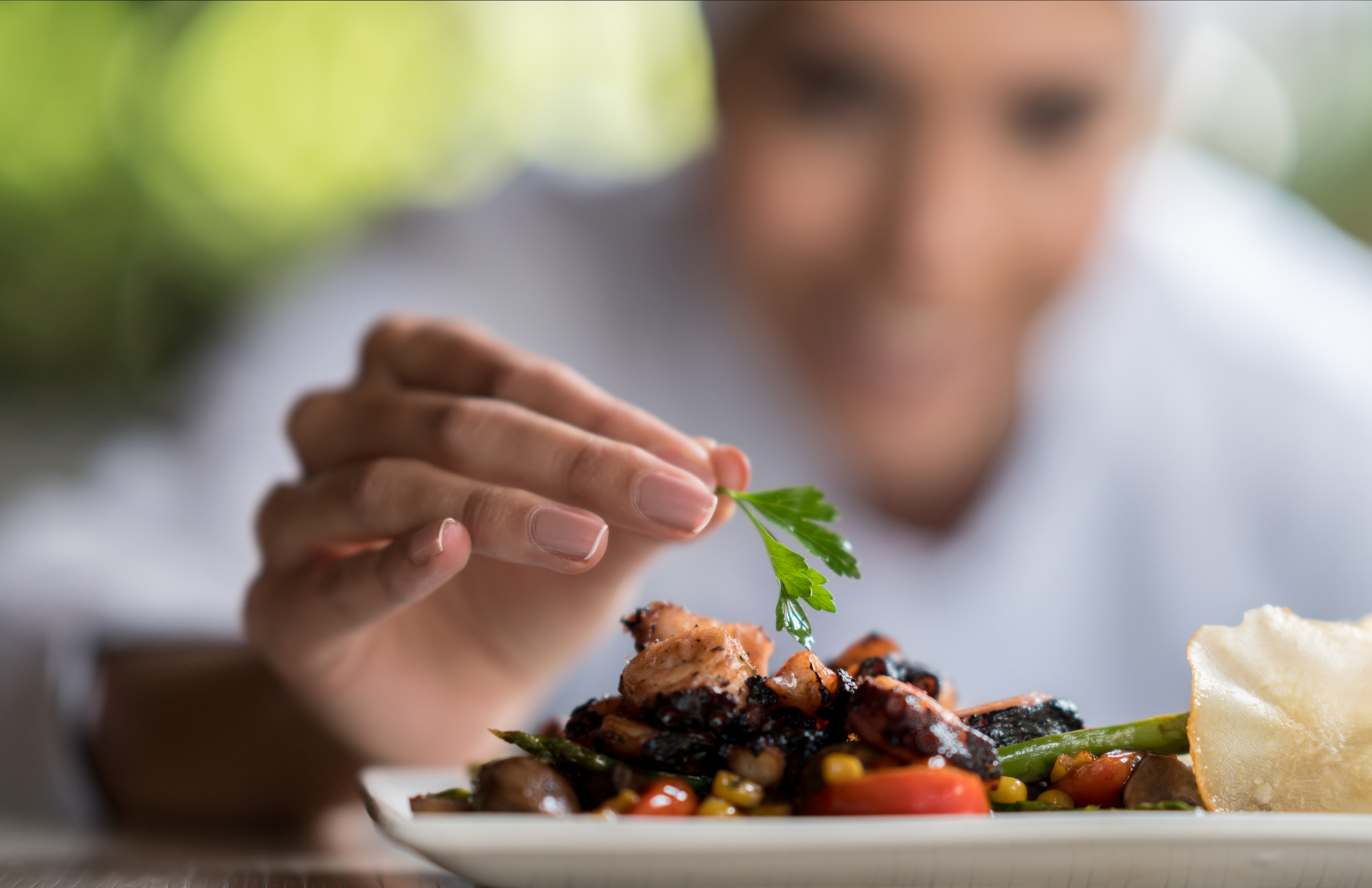 Un chef está decorando un plato de comida con perejil.