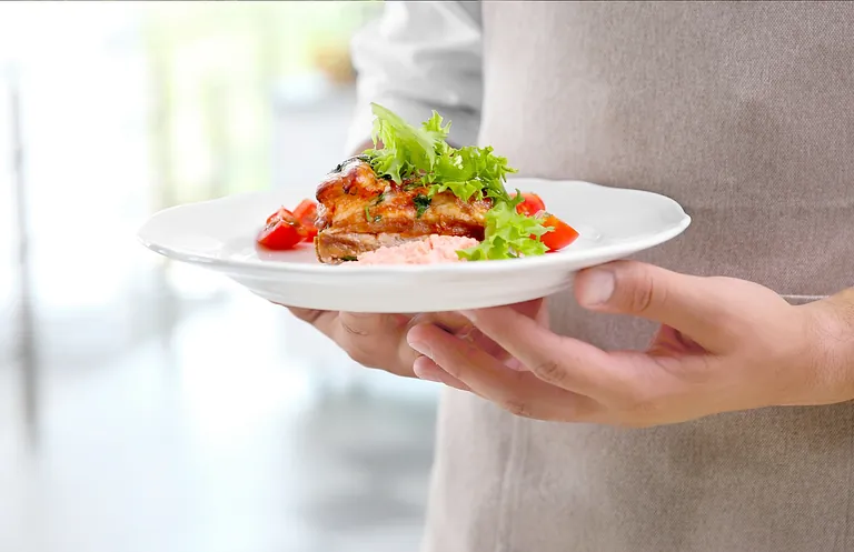 Una persona sostiene un plato de comida en sus manos.