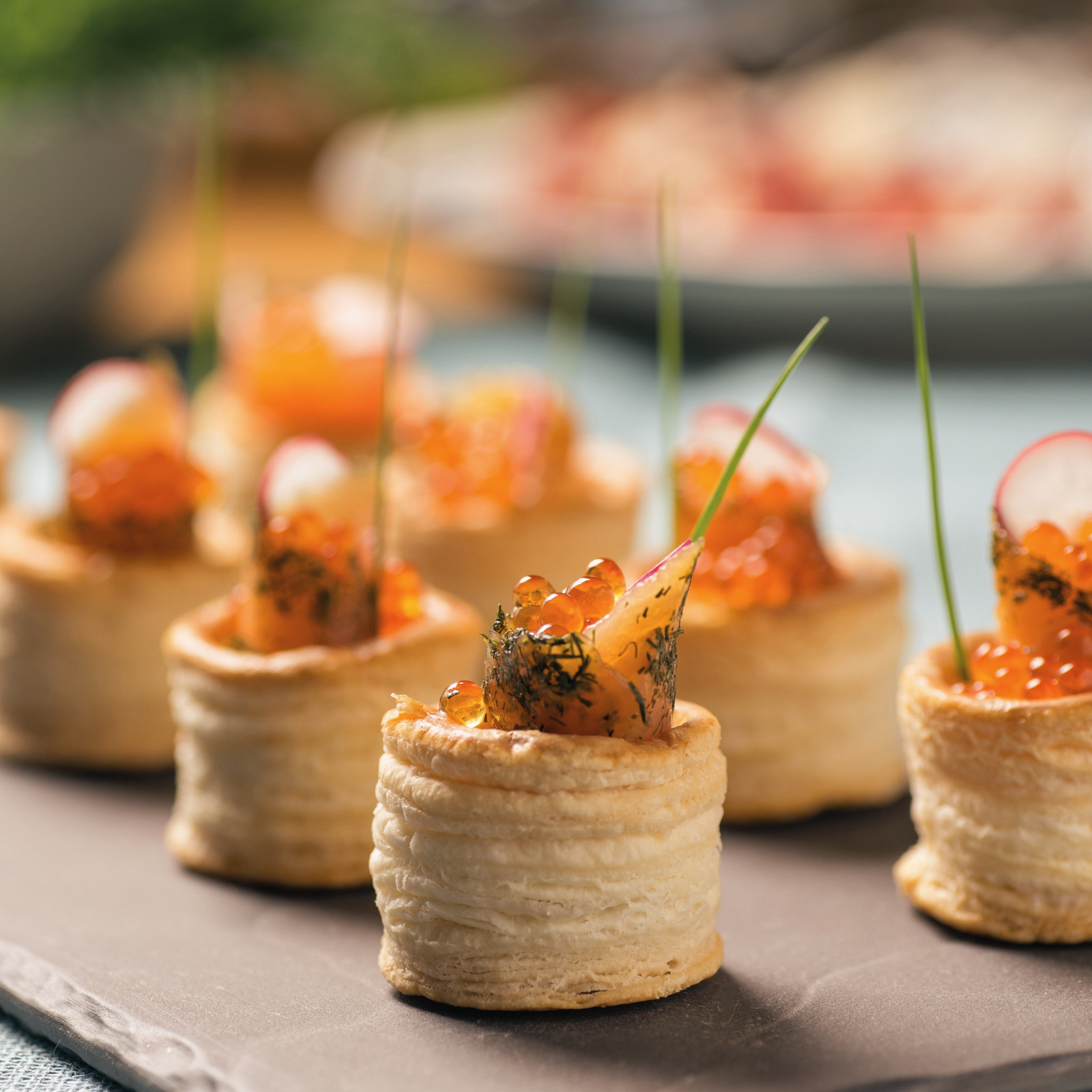 Una bandeja de aperitivos con salmón y caviar sobre una mesa.