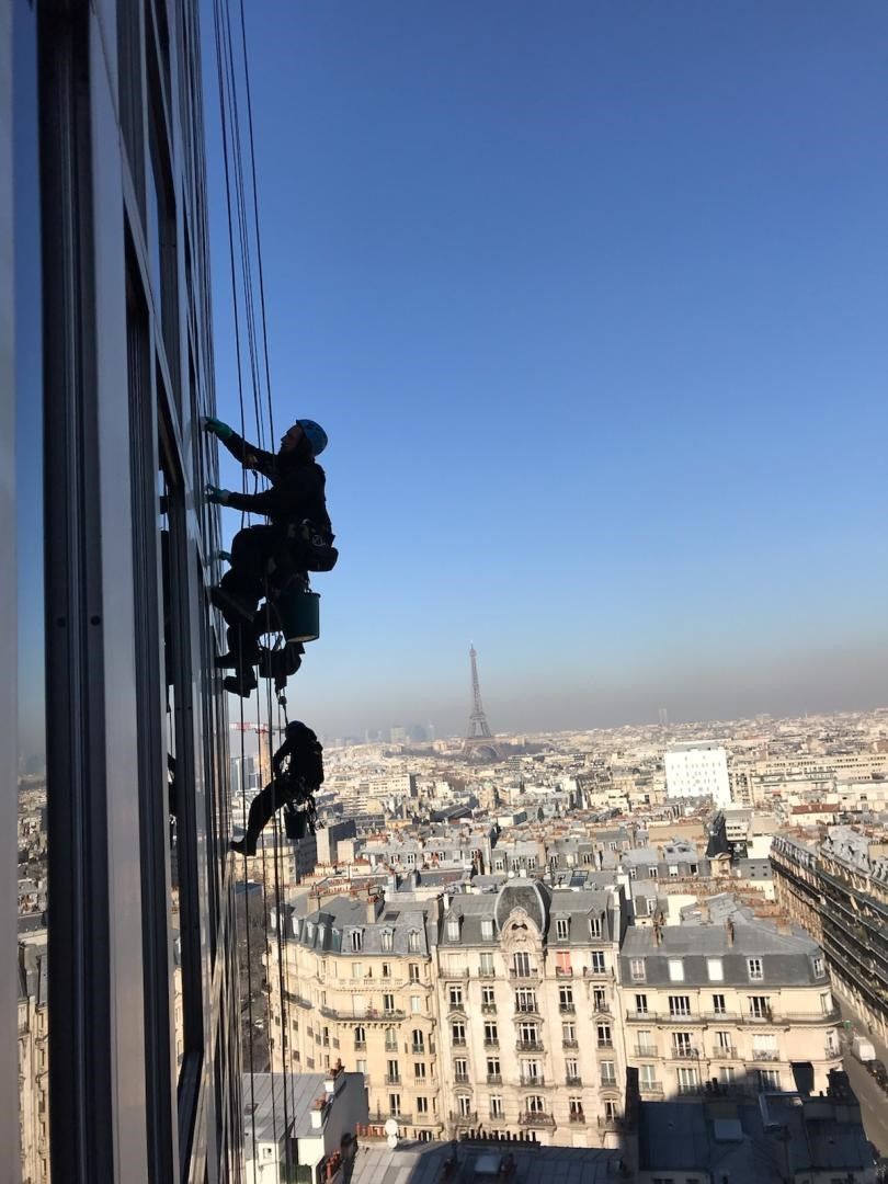 Plusieurs cordistes sur une façade avec vue sur Paris