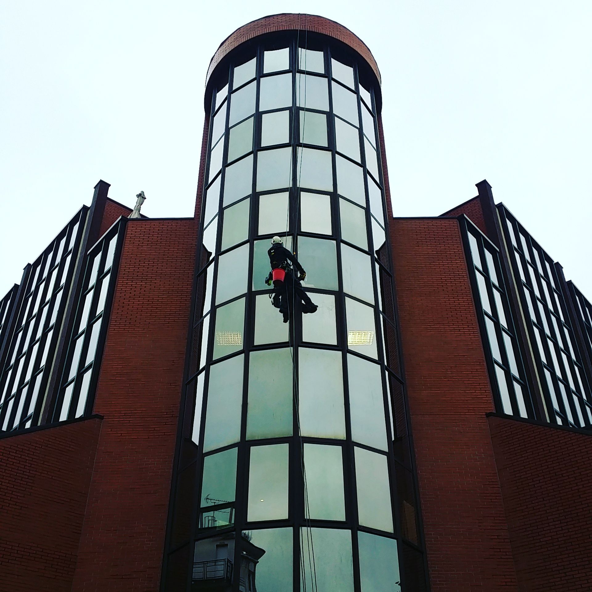 Homme sur façade cylindrique vitrée