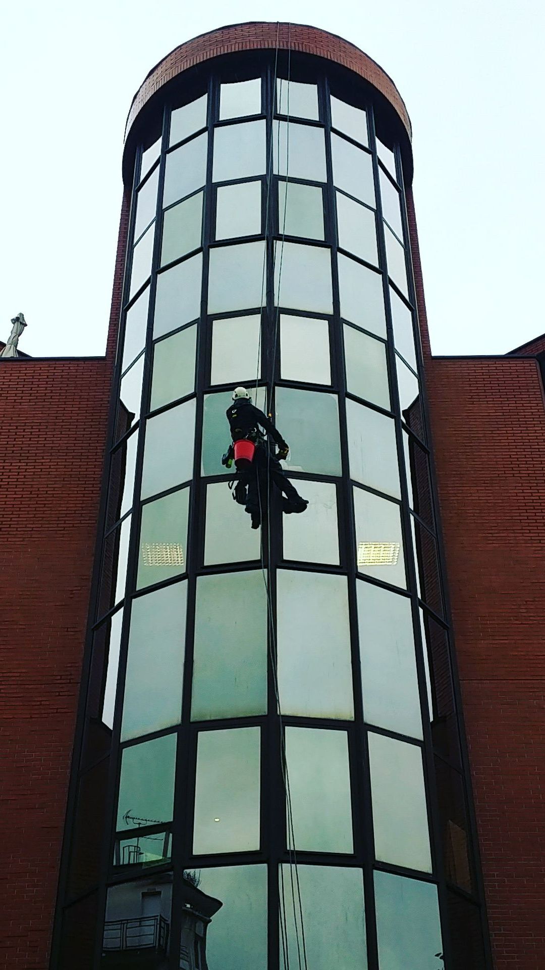 Homme sur façade cylindrique vitrée