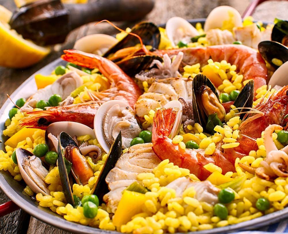 Un primer plano de una paella con mariscos y arroz en una mesa.